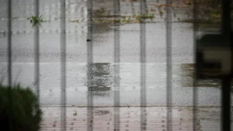 Rain in the puddle on paved road viewed from behind gate bars Stock Footage 153992552