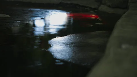 Rain puddle reflecting passing traffic lights in Bangkok Stock Footage 345980862