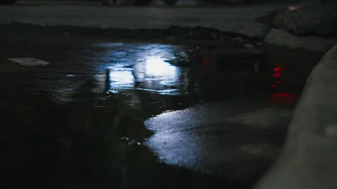 Rain puddle reflecting passing traffic lights in Bangkok Stock Footage 345981250