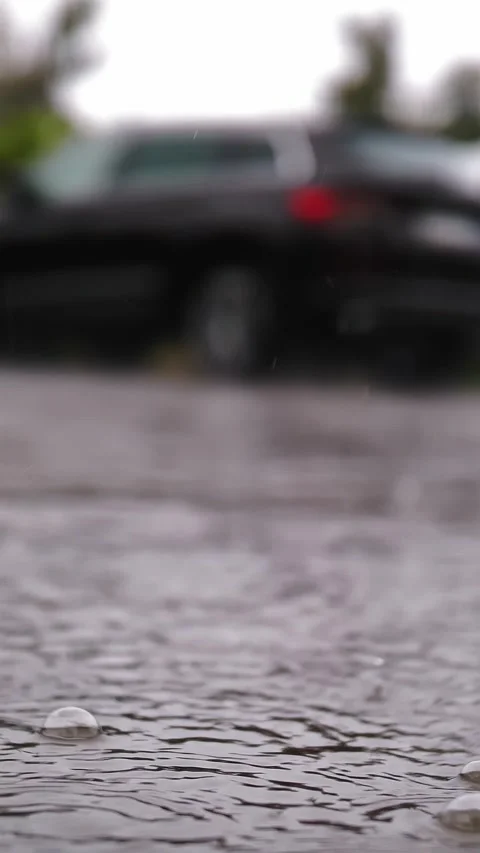 Rain, puddles. raining on parking lot. close-up. raindrops fall into puddles Stock Footage 315437936