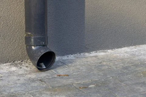 Rain runoff.New plastic drain pipe on a gray plastered wall Stock Photos