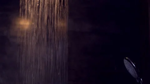 Rain shower water flow down with warm light reflection on black tiles  bathro Video stock 188874571