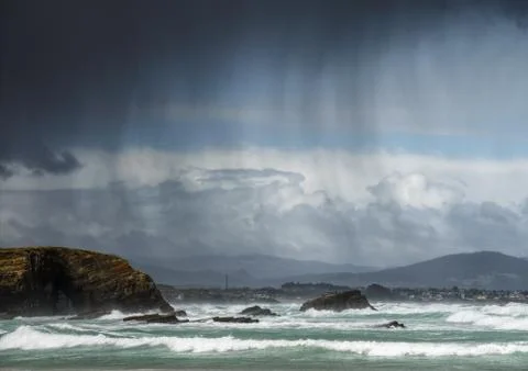 Rain showers blown by the wind between the sea and the cliffs Stock Photos