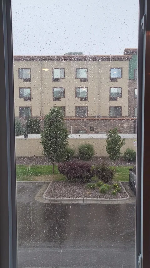 Rain streaks a framed window, blurring view of distant building Vidéo 339641491