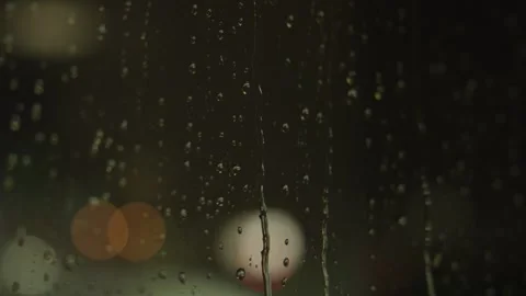 Rain streams down a glass window at night Stock Footage 241498826