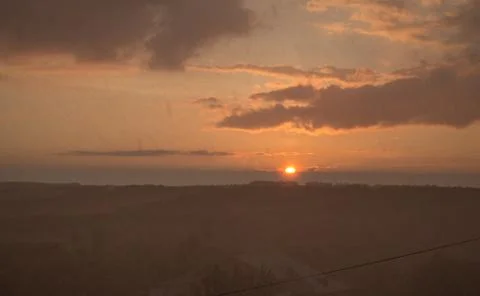 Rain at sunset. Raining over landscape with orange light of sun at sunset. Stock Photos