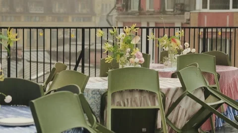Rain on the terrace of a rooftop cafe. Empty wet tables decorated with flowers Stock Footage 318064880
