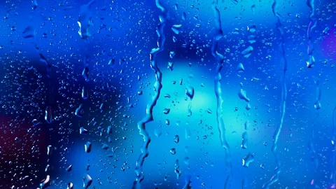 Rain water droplets trickling down the window pane against a blue background Stock Footage 126148582