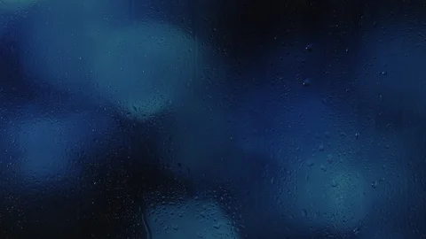 Rain water droplets trickling down the window pane at night, blue background Vidéo 126154700