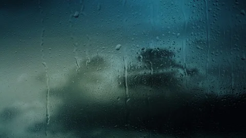 Rain water droplets trickling down the window pane set against clouds Video stock 126157309