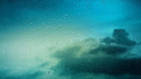 Rain water droplets trickling down the window pane set against clouds Stock Footage 126160197