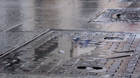 Rain water drops falling into big puddle-Reflection of two people with umbrellas Stock Footage 120188635
