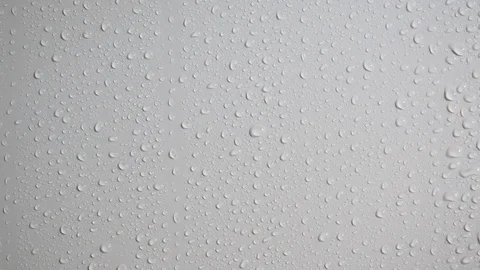 Rain water drops flow down a smooth white wall. Close up. Slow motion Stock Footage 114418468