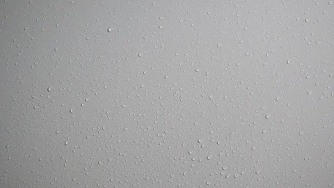 Rain water drops on a smooth white wall. Close up. Slow motion Stock Footage 114418474