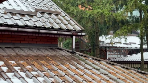 Rain water is falling and flows down the tiled roof into the drainpipe. A green Stock Footage 258380676