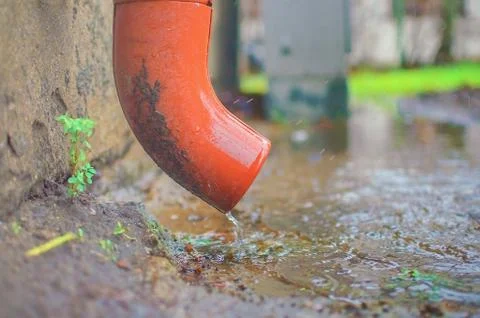 Rain water flowing from drain pipe closeup Stock Photos