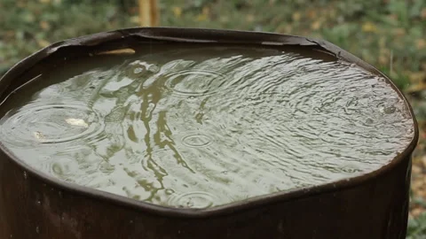 Rain water flowing into an old rusty barrel. Rain drops closeup. Stock Footage 99012137