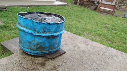 Rain water flowing into old rusty barrel far view Stock Footage 106530549