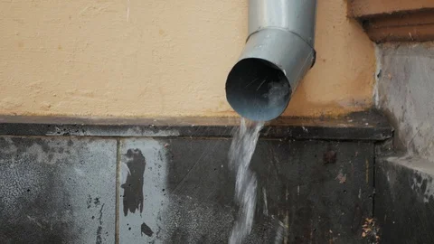 Rain water flows from drain pipe or downspout at building wall, close up Video stock 111928128