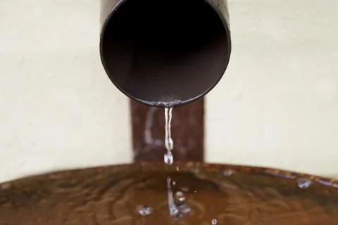 Rain water flows from a plastic drainpipe to the metal barrel Photos