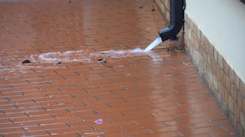 Rain water gushing out of rain gutter on a rainy day Stock Footage 128963311