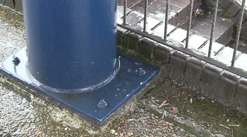 Rain water hitting a blue pillar and brick steps Stock Footage 7138939