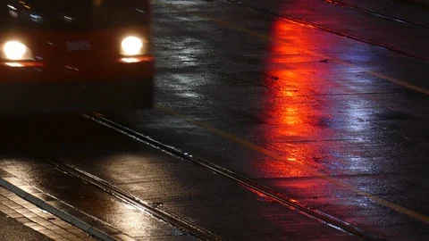 Rain wet road; lights; Tram rails and red water reflection in the rain at dus Stock Footage 99532522