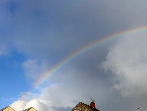 Rainbow Above Cloudy Sky Over Rooftops Foto stock