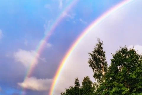 Rainbow after rain in a cloudy sky among dramatic clouds Stock Photos
