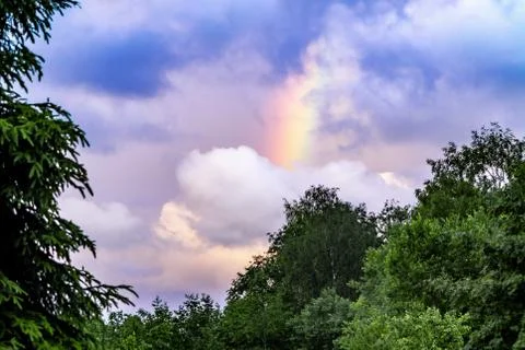 Rainbow after rain in a cloudy sky among dramatic clouds Stock Photos