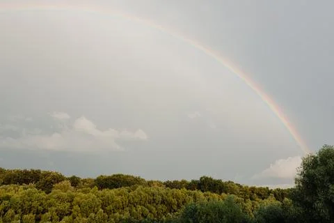 Rainbow after rain on cloudy sky Stock Photos