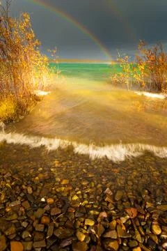 Rainbow and dark clouds over large lake Foto stock