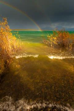 Rainbow and dark clouds over large lake Foto stock