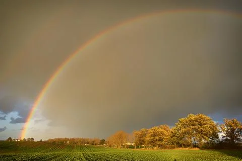 Rainbow and dramatic gray sky with clouds landscape Stock Photos