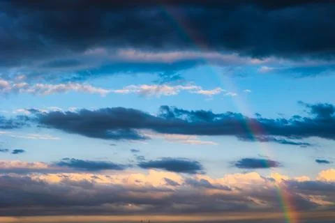 Rainbow and partly cloudy sky on the background Stock Photos
