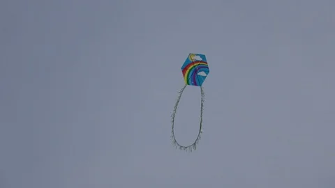 Rainbow and sun painted kite hovers in the dark grey sky Stock Footage 105923852