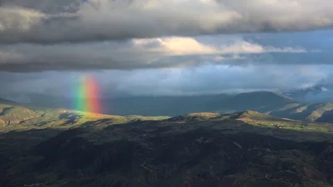 Rainbow appearing after rain over treeless spring hills under cloudy sky Stock Footage 339362211