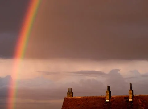 Rainbow arc above the rooftops Stock Photos