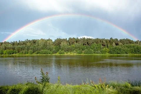 Rainbow arc over trees Stock Photos