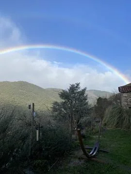 Rainbow arching over rural mountain landscape 스톡 사진