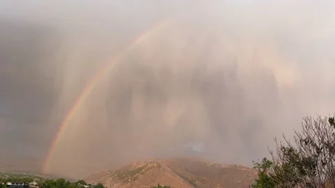 Rainbow arcs over Garni Mountains as rain clouds disperse, revealing vibrant Stock Footage 344723115
