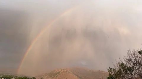 Rainbow arcs over Garni Mountains as storm clouds disperse, revealing vibrant Stock Footage 344844532