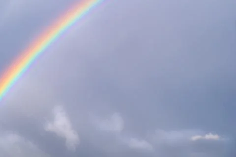 Rainbow on a background of the cloudy sky. Stock Photos