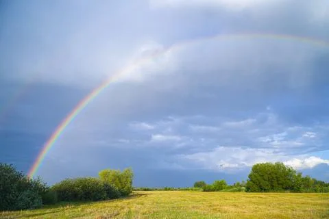 Rainbow on the background of storm clouds over mown meadow Foto stock