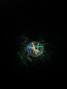 A rainbow ball surrounded by smaller bright objects in the dark Stock Photos