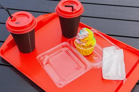 Rainbow cake and two cups of coffee stand on a tray in an outdoor cafe 스톡 사진