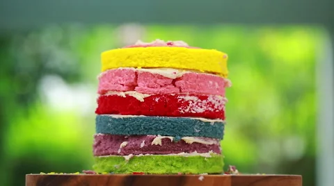 Rainbow cake on turntable on table on green background Stock Footage 51926860