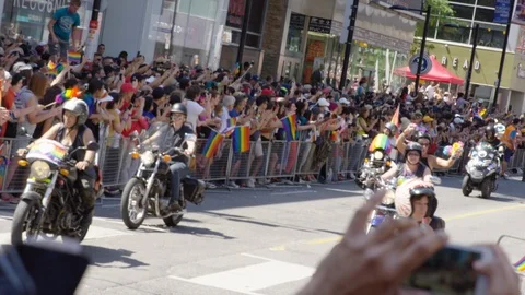 Rainbow clad supporters watch a pride parade float that has stopped to dance and Stock Footage 124344293
