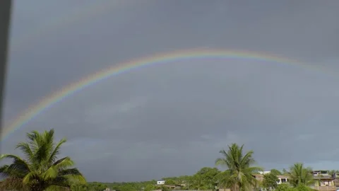 Rainbow in a cloudy sky, over a tropical rural landscape 스톡 동영상 329528637