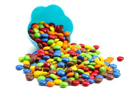 Rainbow Colored Candy Coated Chocolate Buttons in a Fun Blue Bowl Isolated on Foto stock